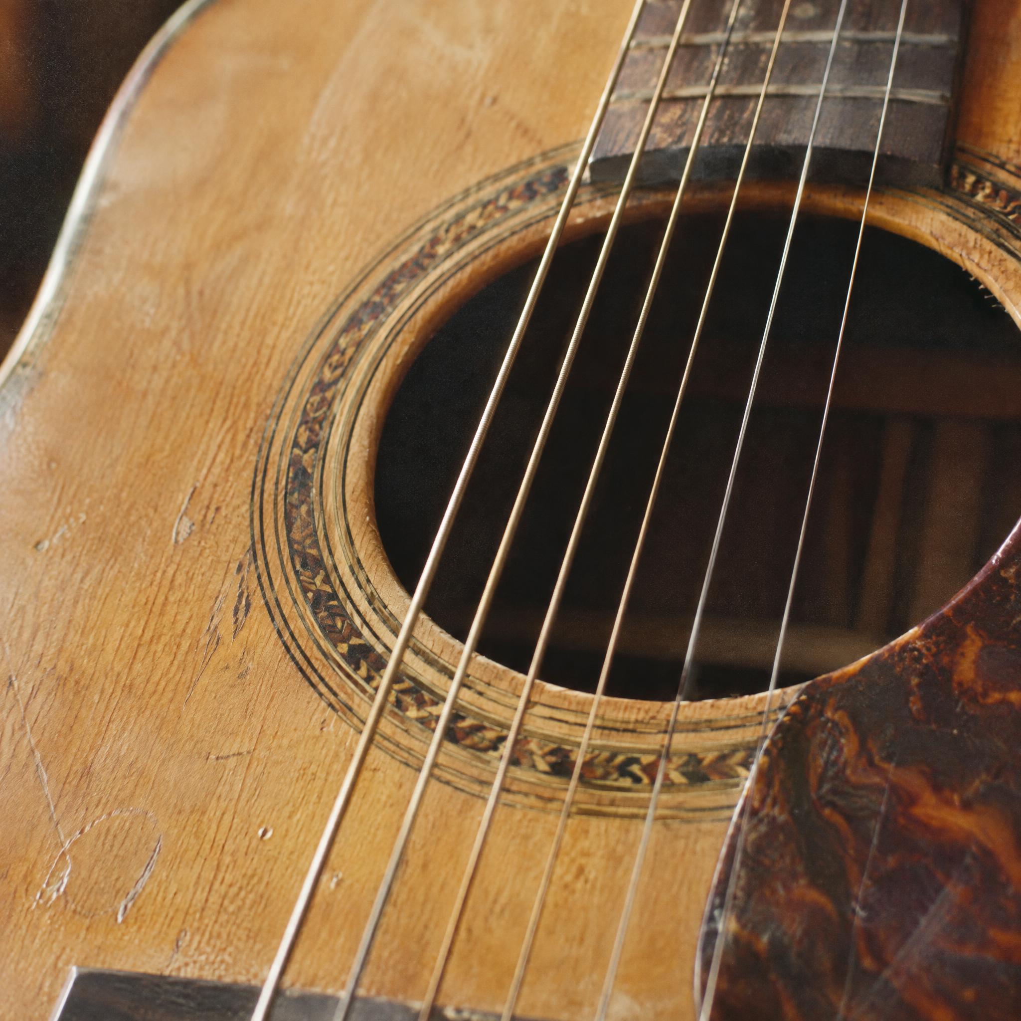 Close-up of a worn acoustic guitar soundhole, rosette and strings with a tortoiseshell pickguard